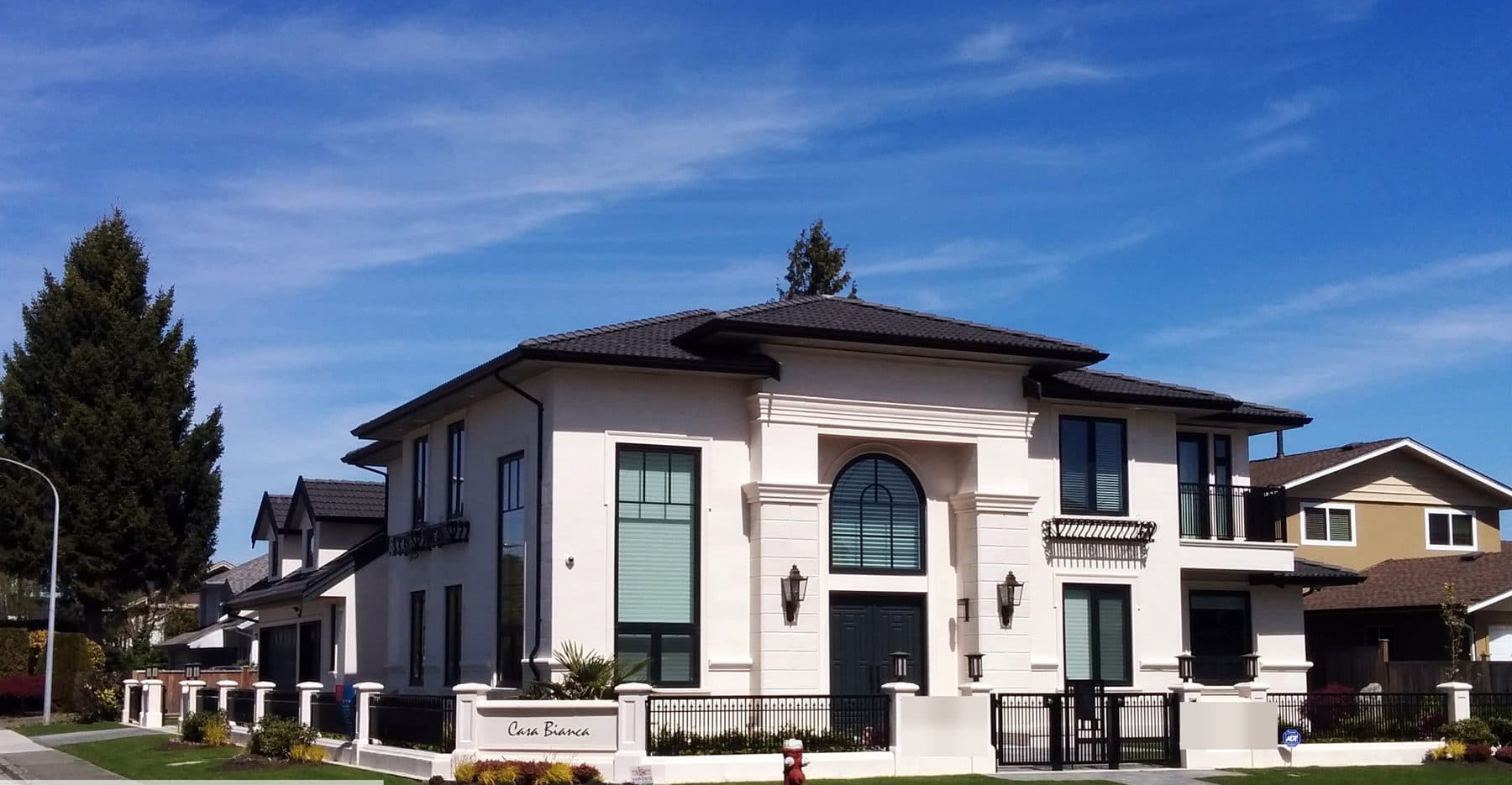 Front exterior of a traditional white single-family home with a formal arched entry